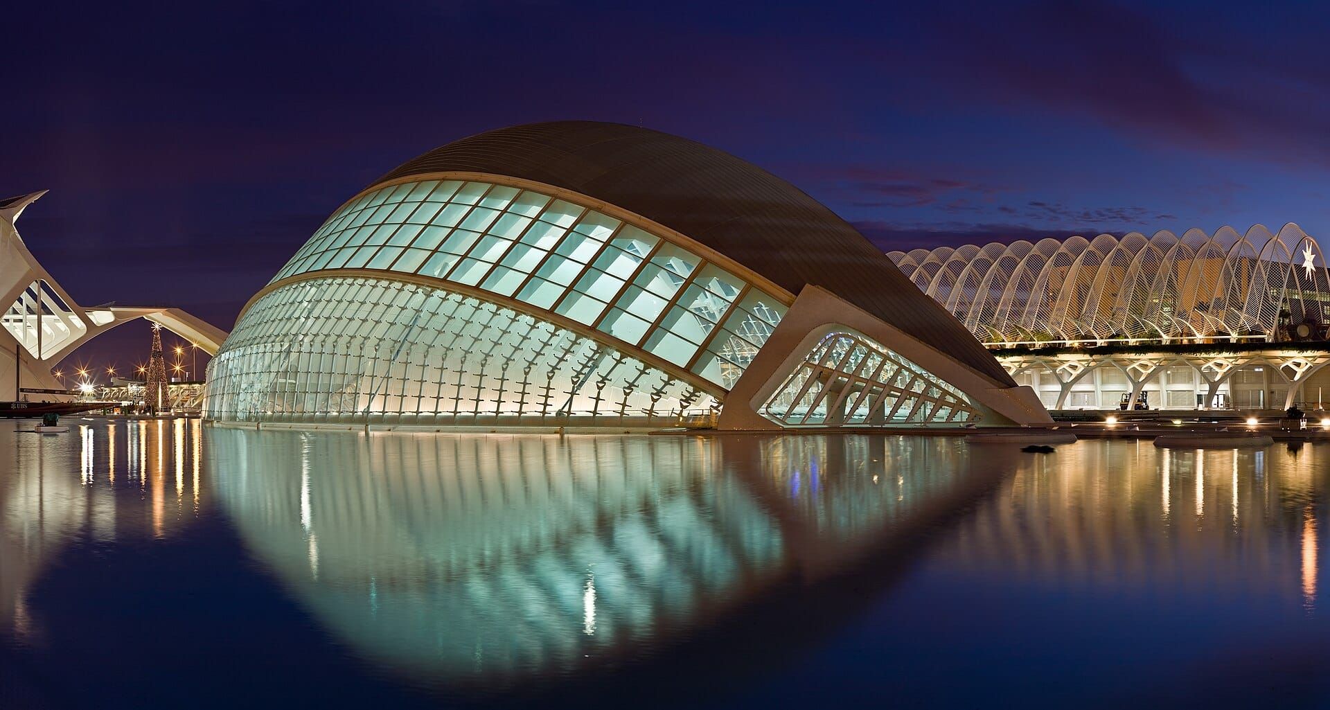 El Hemisfèric iluminado de noche, reflejado en el agua
